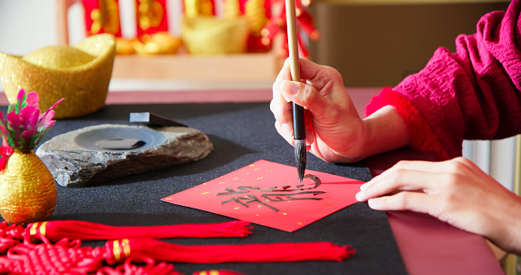 close up asian woman write spring festival couplet to celebrate Chinese new year with word meaning Dragon