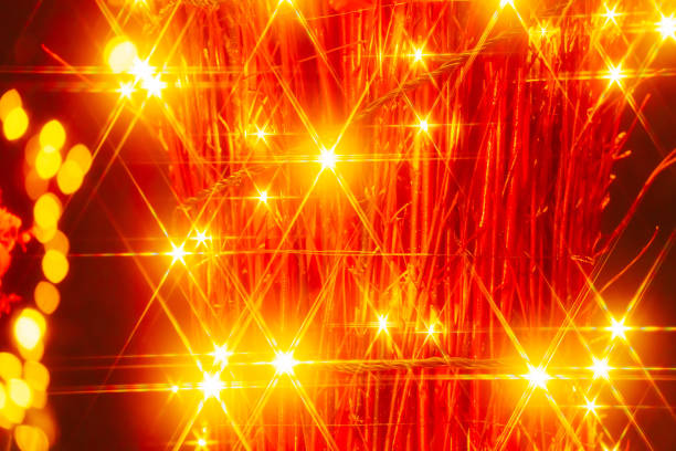 A low-key close-up image of a candle lantern captured at a high angle with long exposure shot, showing some compelling pattern of shadow details amid the vivid color of the candle reflected by its light.