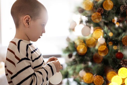 Cute little boy decorating Christmas tree