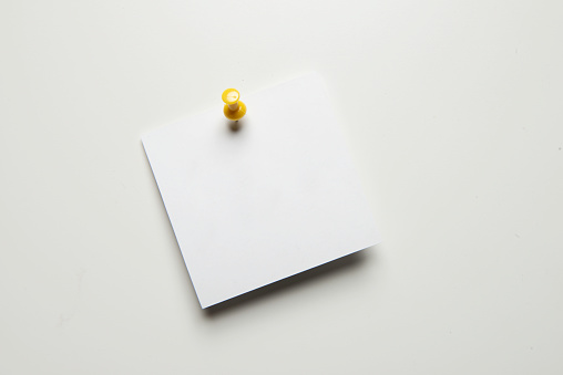 Blank white paper attached with thumbtack on white background.