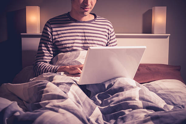istock Young man sitting in bed video chatting 184262760