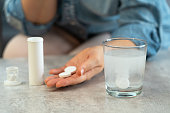 Female hands with pills on background of water glass with effervescent tablet
