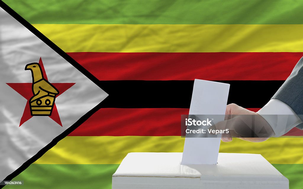 Hombre de voto en las elecciones en zimbabwe front of flag - Foto de stock de Adulto libre de derechos