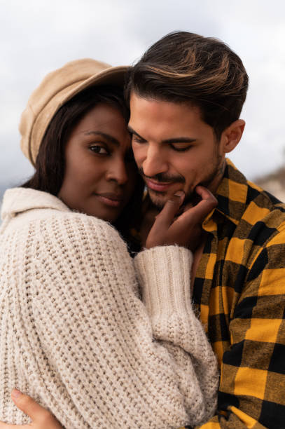 istock Multicultural couple embracing on a cold day in the beach 1842650740