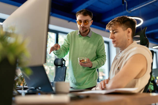 istock Man helping his colleague with a project 1842661136