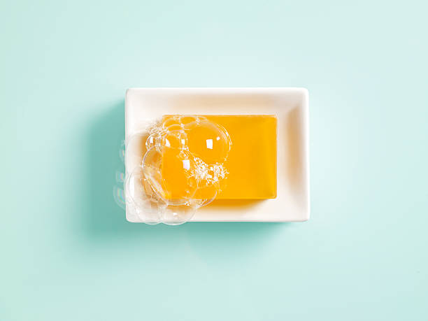 Orange soap in a dish Orange bar of soap in a white ceramic dish on a light green background. bar of soap photos stock pictures, royalty-free photos & images