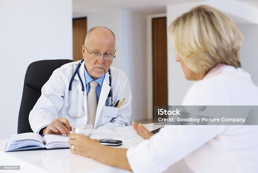Senior mujer hablando con el médico - Foto de stock de 50-59 años libre de derechos