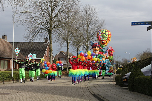 Hulst, Holland - feb 25, 2017: a beautiful big float and a large group of people in colorful rainbow costumes is dancing in front during the carnival parade in the netherlands