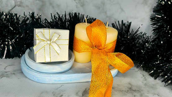 White small gift box, two candles with a ribbon, black tinsel on background
