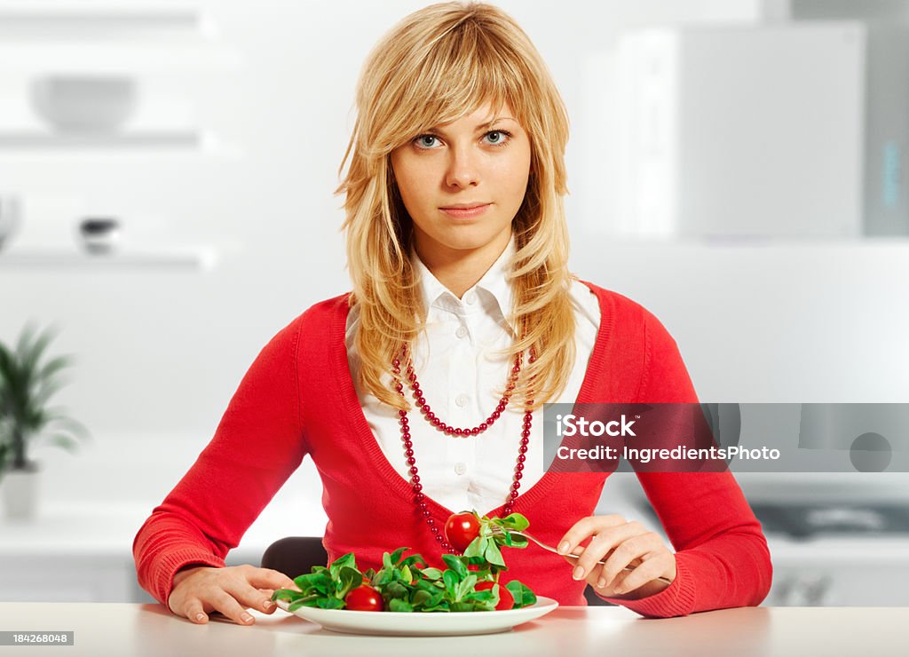 Felice bella donna con un piatto di insalata in cucina - Foto stock royalty-free di Abbigliamento casual