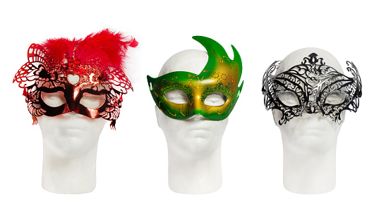 Three multicolored carnival or theatrical masks on mannequin heads, isolated. Clothing and accessories for Christmas or other holidays.
