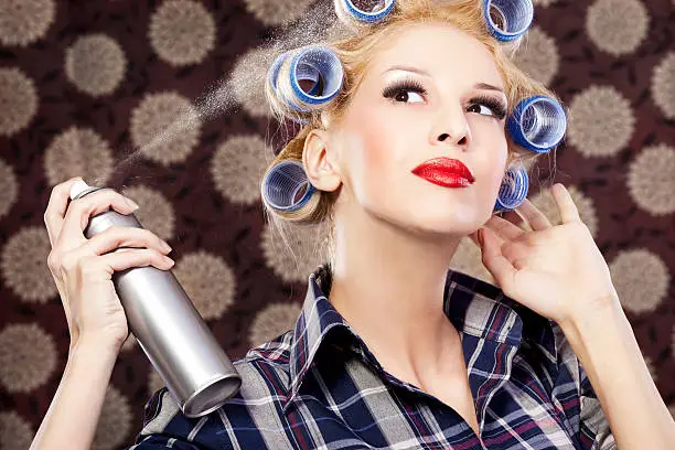 Portrait of an stereotypical housewife Woman hairdressing with hair styling spray