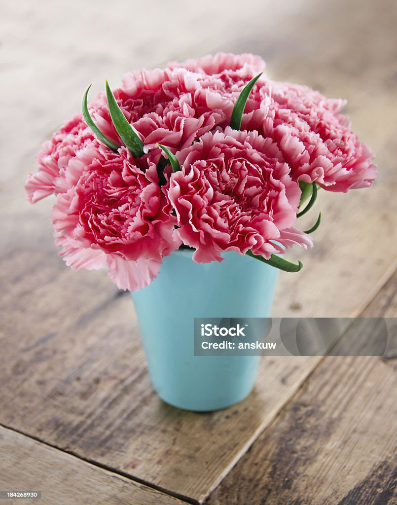 Pink carnations flower bouquet Pink carnations flower bouquet in a blue vase on rustic wooden background Carnation - Flower Stock Photo