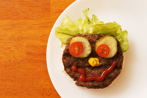 a hamburger with a funny face made of condiments with copy space.
