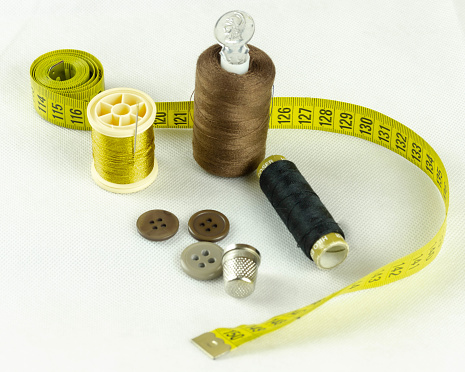 Spools of colored thread such as brown, yellow and black, buttons and metal thimble.