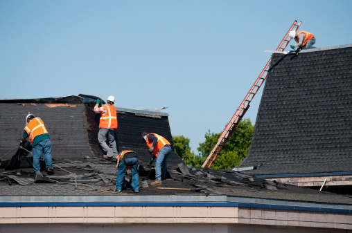 Roofing crew at work removing and replacing roof