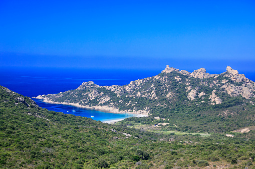 Bay of Roccapina on the island of Corsica, France. On the mountain a Genoese tower and to the right a stone looking like a lion. Sailboats anchoring in the bay.