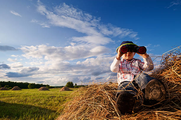 Photo of Child on mounds of hay with binoculars