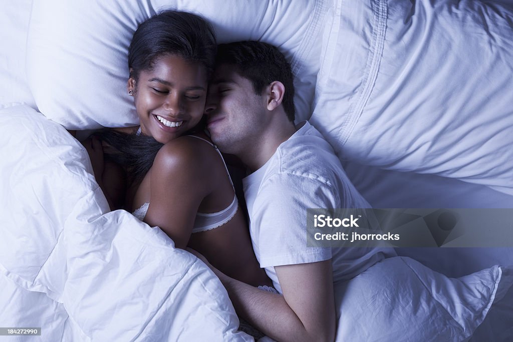 Casal jovem feliz na cama - Foto de stock de Dormir abraçados royalty-free