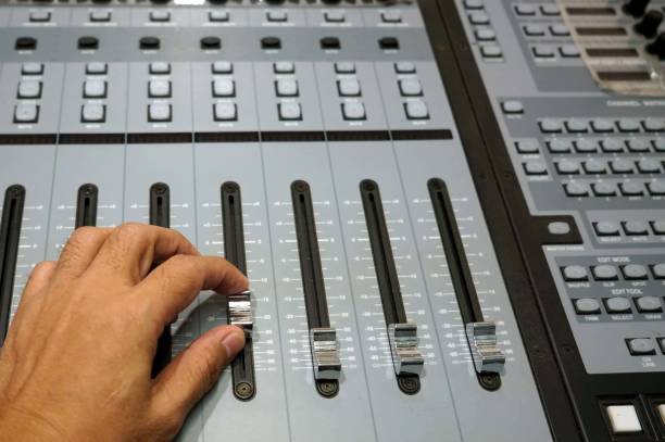 Sound engineer working on mixing console, closeup of hands doing adjust a fader.