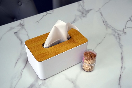 Close up wooden box with a napkin on a table in a restaurant.