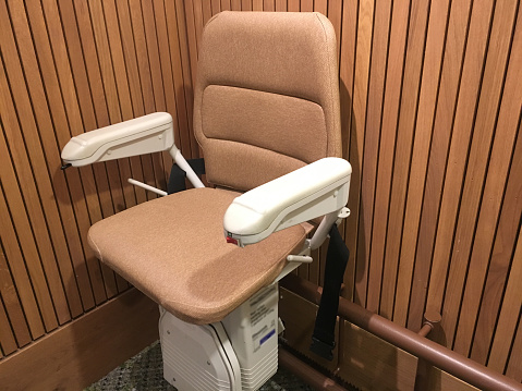 Close-up shot of an automatic stair lift chair on staircase for disabled and elderly people installed in a residential building.