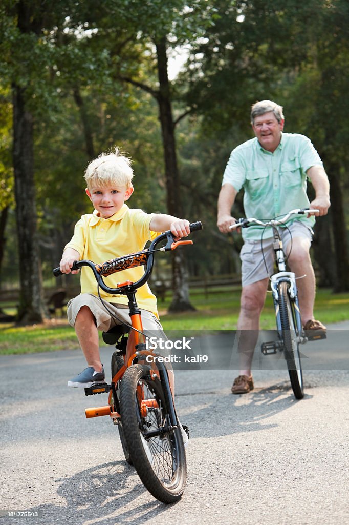 Petit garçon d'équitation de vélo avec son grand-père - Photo de Faire du vélo libre de droits