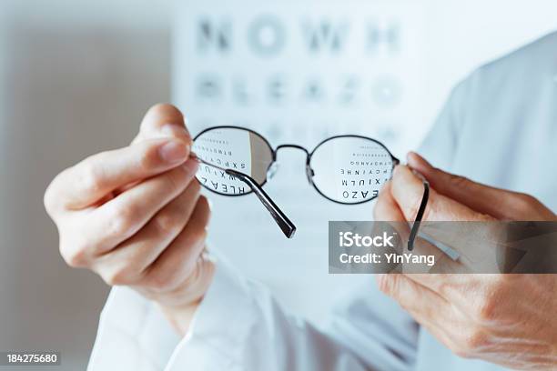 Optometrista Segurando Óculos Olho Gráfico Realização De Exame Hz - Fotografias de stock e mais imagens de Adulto