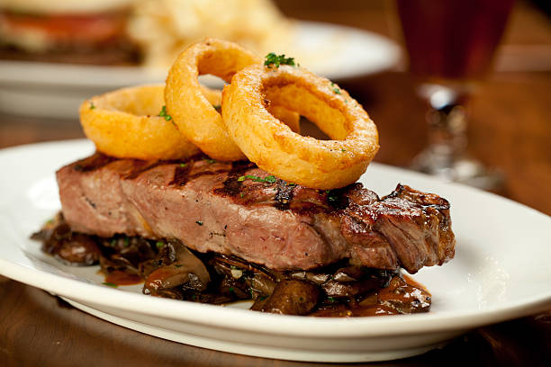Steak on mushrooms with onion rings meal served in restaurant stock photo