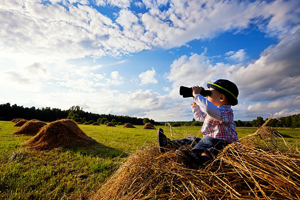 Photo of Little boy sitting on mounds of hay