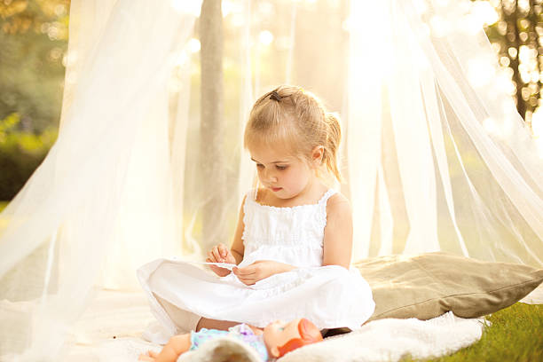 Little Girl in Canopy Under Tree with Doll stock photo