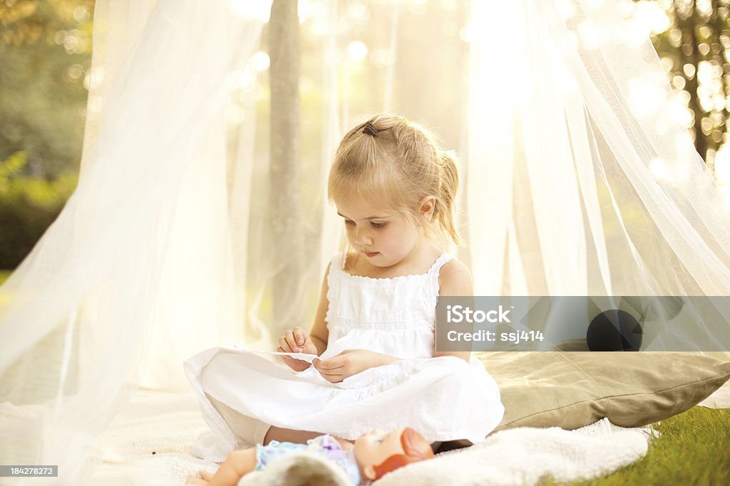Маленькая девочка в Canopy под дерево с кукла - Стоковые фото Задний или передний двор роялти-фри