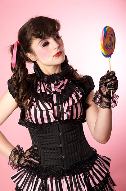 istock Porcelain doll model looking at big lollipop. 184278609