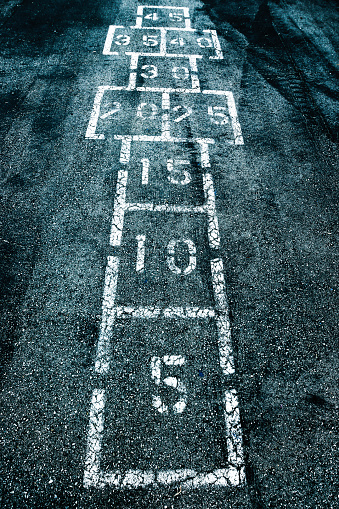 Classic American game of hopscotch stenciled onto a playground. Striking high-contrast image with numbers and geometric shapes. High quality photo