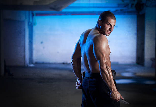 Underground Fighter "Storng, muscular man standing in the underground garage with knife in his hand .... This photo is available on istockphoto only." underground fighters stock pictures, royalty-free photos & images