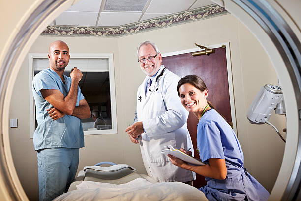 View of healthcare workers through CT scanner View of healthcare workers through CT scanner male nurse male healthcare and medicine technician stock pictures, royalty-free photos & images