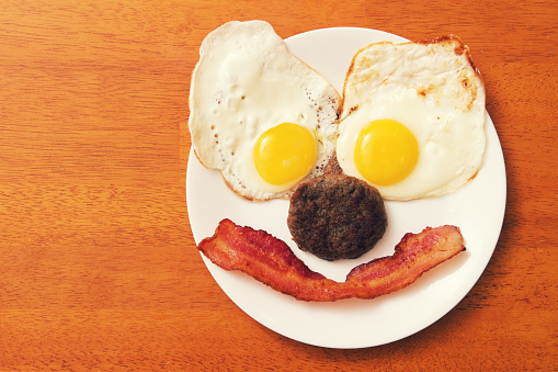 breakfast food plate with a smile made of eggs bacon and sausage. 