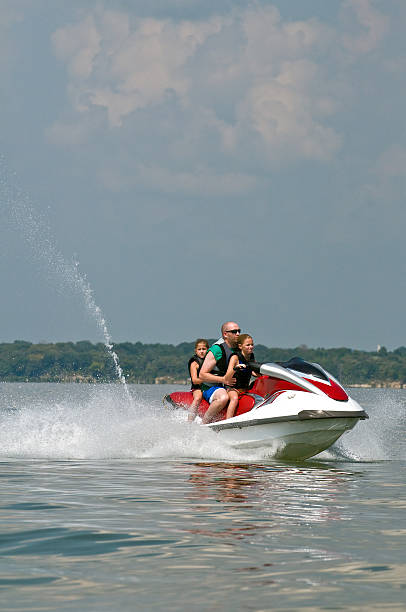 Three people riding on a personal water craft.
