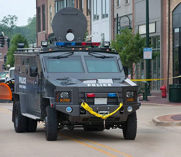 side and frontal veiw of a armored vehicle used by police swat team stopped in the street in front of shops