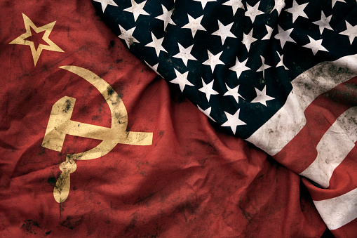 Low key photography of grungy old Soviet Union and United States of America flags. USSR, CCCP, USA.
