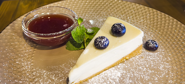 vanilla cheesecake with blueberries, mint leaves, strawberry jam, powdered sugar