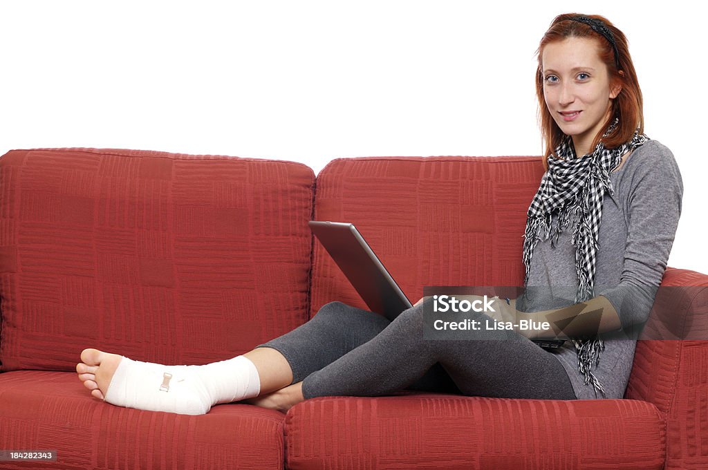 Girl Using PC on Sofa with Ankle Bandage Girl on sofa with ankle bandage 20-24 Years Stock Photo