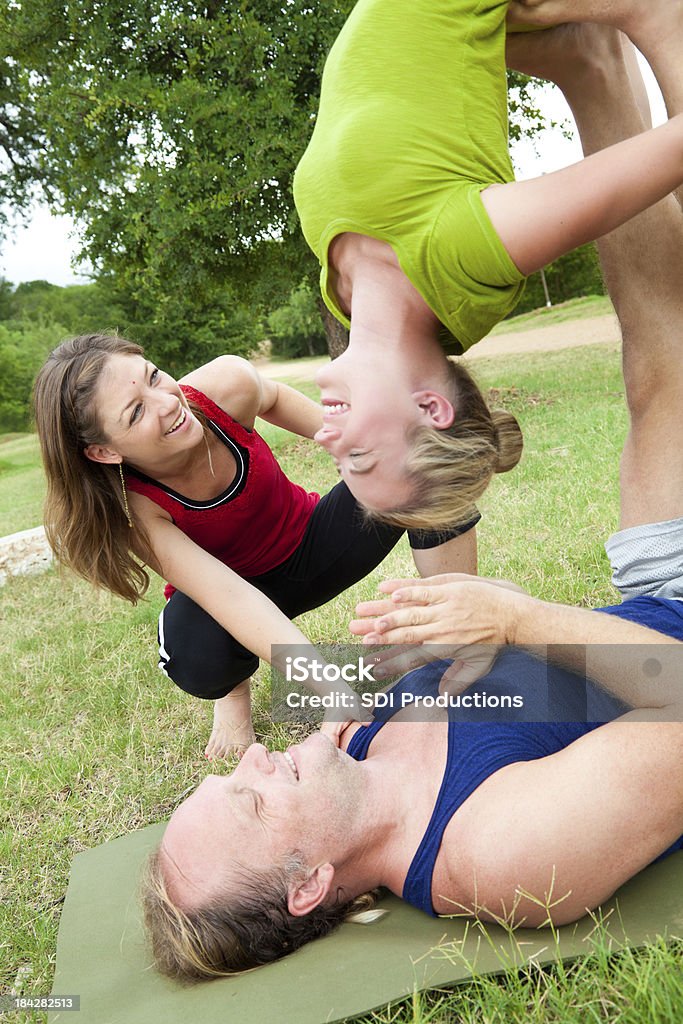 Acroyoga instrutor ajudando o homem e jovem mulher com uma Pose - Foto de stock de Acroyoga royalty-free