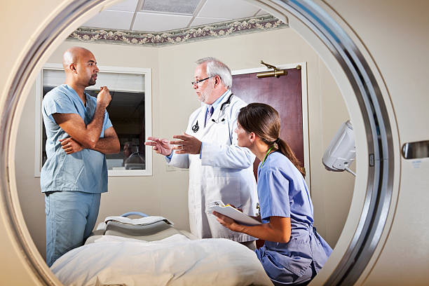 View of healthcare workers through CT scanner View of healthcare workers talking through CT scan. male nurse male healthcare and medicine technician stock pictures, royalty-free photos & images