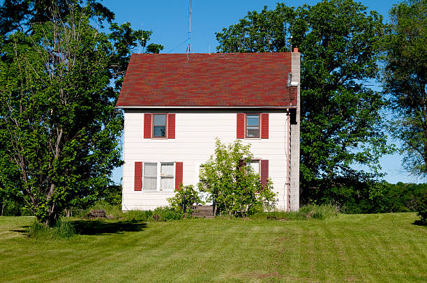 Plymouth, MA, USA - September 21, 2012: Luxury Elegant New England Home with white clapboard exterior and black window shutters in Plymouth, Massachusetts, USA. Red brick sidewalk, green bushes and trees are in foreground. Overcast sky is in background. HDR photorealistic image.