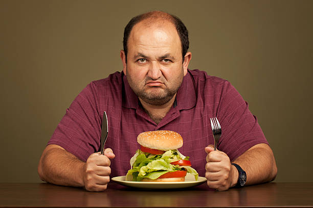 Man eating a burger with loads of salad Man excited about eating a burger with a lot of salad and no patty brat burger stock pictures, royalty-free photos & images