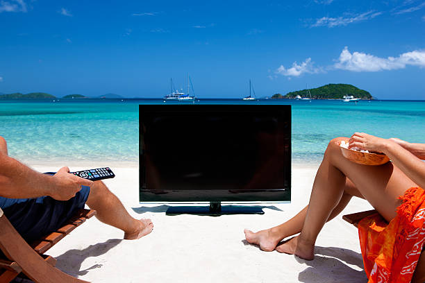 pareja viendo la televisión en una playa tropical del caribe - women sarong beach white fotografías e imágenes de stock