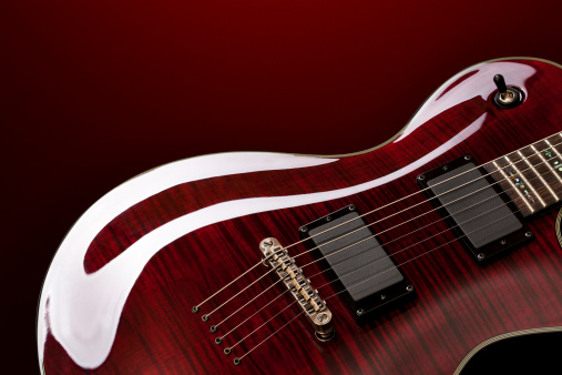 Close-up on electric guitar on red background.