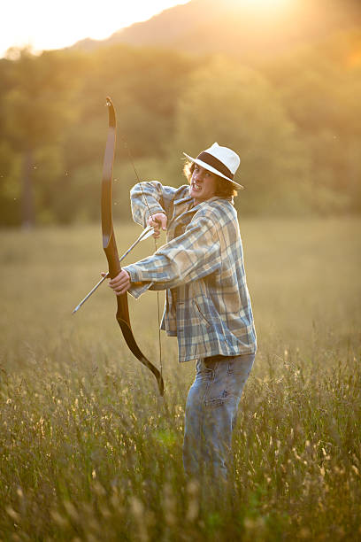 istock Young hunter firing bow and arrow 184284988
