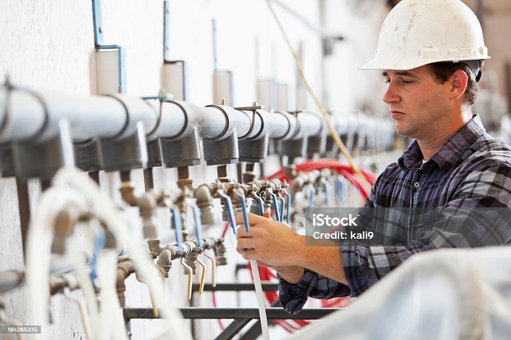 Industrial worker at manufacturing facility Worker, 30s, attaching hose to air pipe at manufacturing plant. 30-34 Years Stock Photo